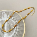 Détail d'un collier de perles vintage avec pierres minérales jaunes et perles dorées - Orange