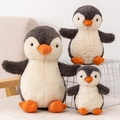 Tre peluche a forma di pinguino di varie dimensioni con pelliccia grigia e bianca e becchi arancioni - Pinguino Arachide / 21cm