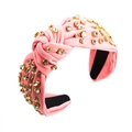Close-up of a pink knotted baroque headband featuring sparkling crystals on a textured fabric - Pink
