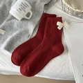 Dunkelrote Wollmischsocken mit weißer Schleife auf gemütlichem weißem Bettlaken - Einheitsgröße / Rot