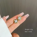 Detailed view of rotating four-leaf clover earrings with sparkling white crystals - Gold
