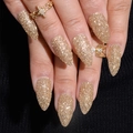 Unghie finte dorate glitterate di media lunghezza a stiletto su modella - Oro Scintillante Appuntito Medio
