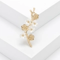 Elegant gold flower branch brooch with white mother of pearl petals on a white geometric stand - Gold