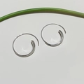 Detail of silver hoop earrings with a sleek curved design and a high-polished metallic finish - Silver Smooth Regular (60#)