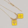 Handgefertigte Boho-Perlenkette mit gelben quadratischen Anhängern und Goldkette - Doppelquadrat-Metallkette
