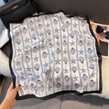 Detail of square silk scarf with seashell print laid on fur beside a black handbag - W-462 Black