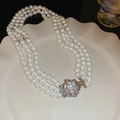 Gros plan d'un collier de perles blanches à trois rangs avec fermoir floral en argent - 11# Collier-Fleur Argent Losange