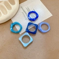 Detail of five blue ink-wash acrylic rings set against a minimalist textile background - Blue Set (Five Pieces)