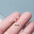 Macro shot of 3mm rose gold mini flower stud earring with white crystal on a finger - 3mm / Gold