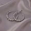 Elegant silver beaded hoop earrings featuring faceted metal spheres on gray silk fabric - E-053---Platinum