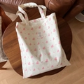 Detailaufnahme der Baumwolltasche mit Blumenmuster und Stoffetikett auf Holztisch - Beige Basis Grau Punkt Rosa Floral