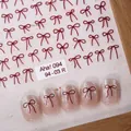 Minimalist deep red bow nail art sticker model 094 on shimmering nude pink nails - Aha-9403 Red Bow
