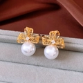 Detailed close-up of gold hollow bow earrings with shiny zircon and white pearls - Gold Hollow Bow White Pearl Earrings