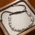 Detailed macro of vintage silver fish charms and dark brown hand-braided cord bracelet - 8 Small Fish Bracelet