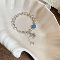 Detail of star charm and blue bead on brushed silver beaded bracelet in a shell tray - Brushed Beads with Star and Smiley Pendant / Silver-Blue