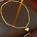 Detalle del collar de doble capa chapado en oro con colgante de corazón y piedras - Dorado