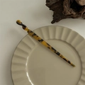 Close-up of tortoise shell pattern hair stick with twisted design on ceramic plate - Hair Stick