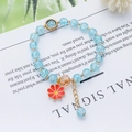 Detail of light blue crackle bead bracelet with daisy pendant and golden extender chain - Daisy Style 1 / Lake Blue