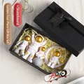 Set regalo statuette astronauti oro e bianco con skateboard in scatola nera con nastro - Set Scatola Regalo da 4 Pezzi Oro + Skateboard