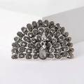Macro shot of silver-tone peacock brooch featuring sparkling grey rhinestones and metalwork - Black