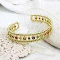 Macro-opname van verstelbare gouden armband met kleurrijke zirkoonstenen op wit kant - Stijl 1 12.5mm Breed