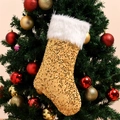 Golden sequined Christmas stocking with white faux fur trim hanging on a festive tree - Gold