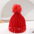 Detail of red knit beanie featuring fluffy pom-pom and elegant pearl accents on the cuff - One Size / Red