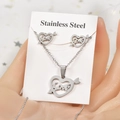 Detailed view of silver stainless steel heart and arrow jewelry set held in hand - Heart with Arrow
