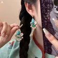 Detail of vintage bohemian earrings with turquoise stone and white floral accents on model - 20# 925 Sterling Silver Earring Post - Gold & Blue