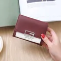 Three-fold burgundy and cream leather mini wallet with square metal buckle in hand - Burgundy