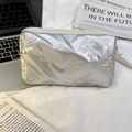Detail of silver quilted makeup bag with embossed bow patterns and metal finish surface - Small Bow Silver