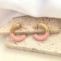 Détail de boucles d'oreilles C dorées et roses sur travertin beige et tissu en soie - Or + Rose