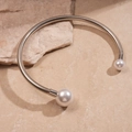 Detail of silver metallic choker featuring two large white pearls on a textured rock surface - Neck Ring - Silver
