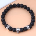 Macro shot of lava stone beads and detailed silver skull charm on a punk style bracelet - Skull