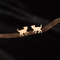 Dettaglio macro di orecchini a forma di gatto in oro rosa esposti su un ramo di legno - Oro rosa