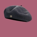 Detailed view of dark grey wool beret featuring a signature golden metal logo button - M / Dark Gray