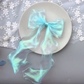 Close-up of blue iridescent organza bow hair clip on a beige plate with white lace - 1221 Iridescent Blue