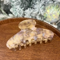 Detail of pearlescent beige and lilac acetate hair claw clip on wooden tray - Beige Starry Purple - Round Top 8-Teeth