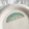 Detalle de un peine de acetato en forma de medialuna con textura de mármol azul en bandeja - Degradado Azul Lago Púrpura