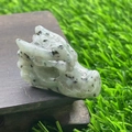 Hand-carved light green natural stone dragon head figurine with dark spots on wood - Kiwi