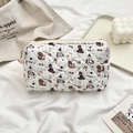 Close-up of quilted cream makeup bag featuring cute cartoon puppies and zipper closure - Skating Dog