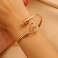 Detail of gold-tone heart-shaped wire-wrapped bangle on a model's wrist with warm lighting - Heart Wire Wrapping Open Bangle (H-75) / Gold