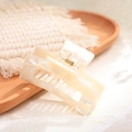 Close-up of marble patterned acetate claw clip with golden spring on wooden tray - Pearl White