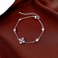 Detalle macro de pulsera de trébol bañada en oro con circonitas sobre satén rojo - Estilo de Trébol de Cuatro Hojas Hueco / Plateado