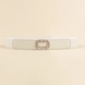 Close-up of white elastic waist belt with a golden rhinestone rectangular buckle detail - White