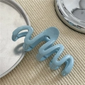 Dettaglio della molletta per capelli a onde azzurra su fondo in tessuto beige - Blu