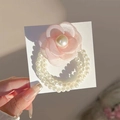 Gros plan sur l'élastique fleur de camélia rose avec triple rang de perles - Style Perle Camélia / Rose