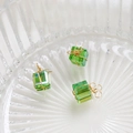 Macro-opname van mini groene kristallen geschenkdoos hangers met gouddraad op glazen tray - Helder Groen