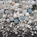 Macro shot of 8mm mixed glass beads with butterfly charms and gradient blue seed beads - White
