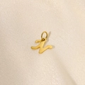 Detailed close-up of 14K gold plated letter N pendant on smooth beige silk fabric - Letter-N